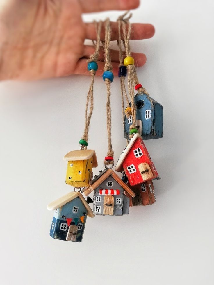 a hand is holding some small houses hanging from strings