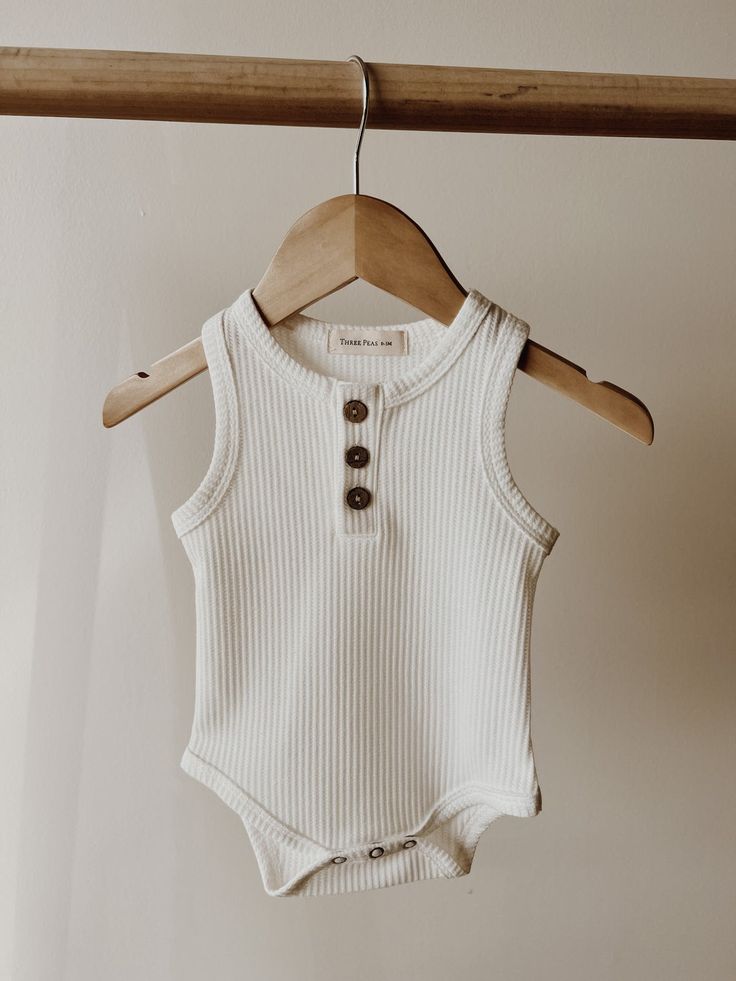 a white bodysuit hanging on a wooden hanger