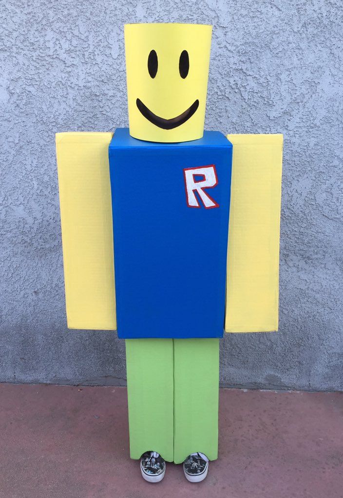 a cardboard man with a smile on it's face and arms, standing in front of a wall