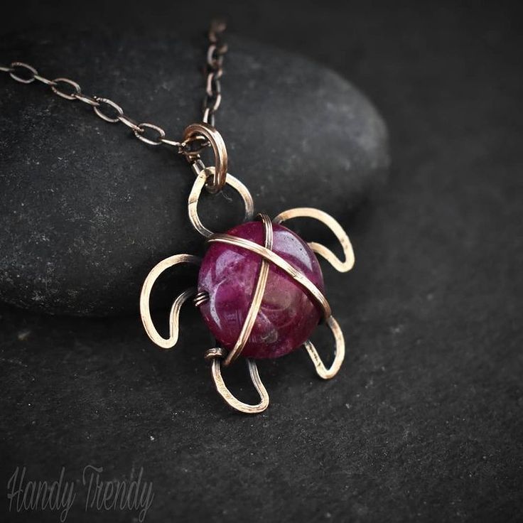 a red stone sitting on top of a metal chain