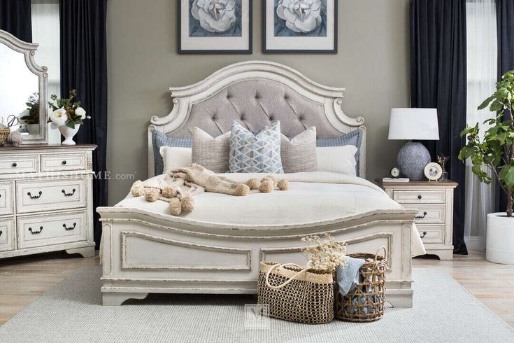 a white bed sitting in a bedroom next to two pictures on the wall above it