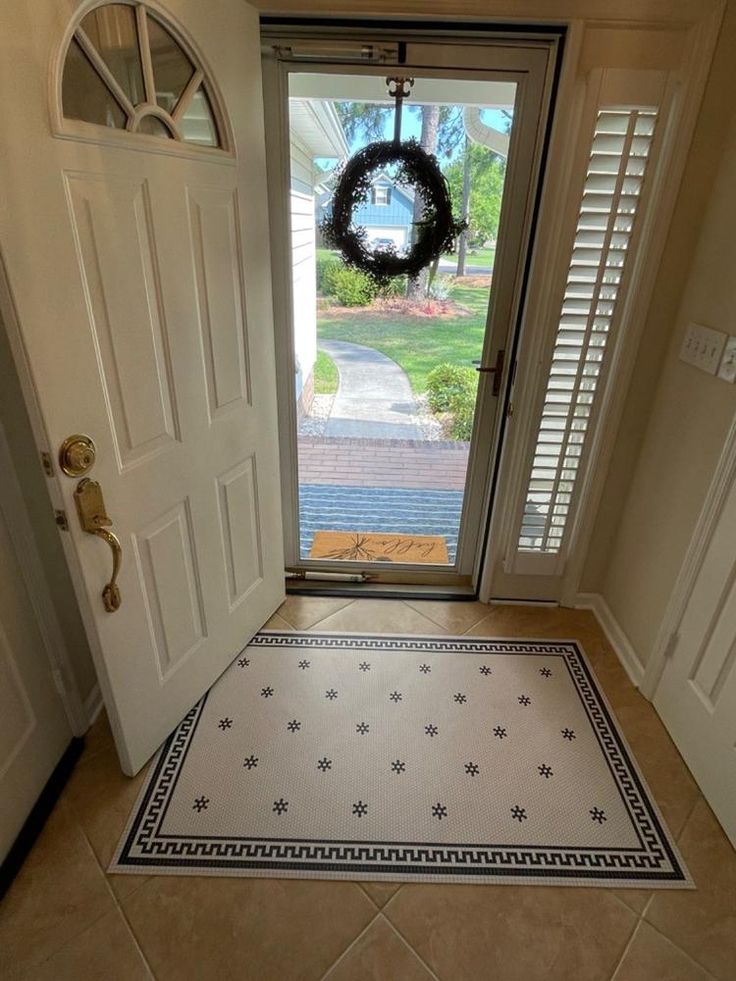 a door with a wreath hanging on it's side next to an entry way