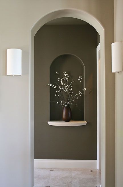 a vase with flowers is sitting on a shelf in the corner of a hallway between two walls