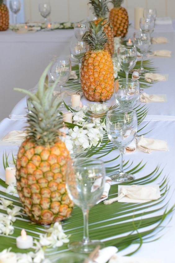 there are pineapples on the table with wine glasses and place settings for them