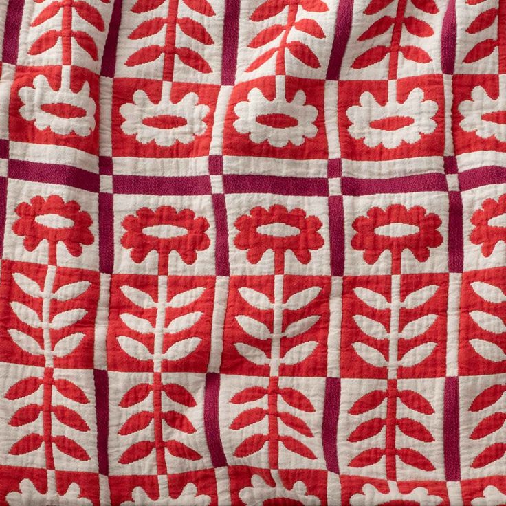 a red and white quilt with flowers on it