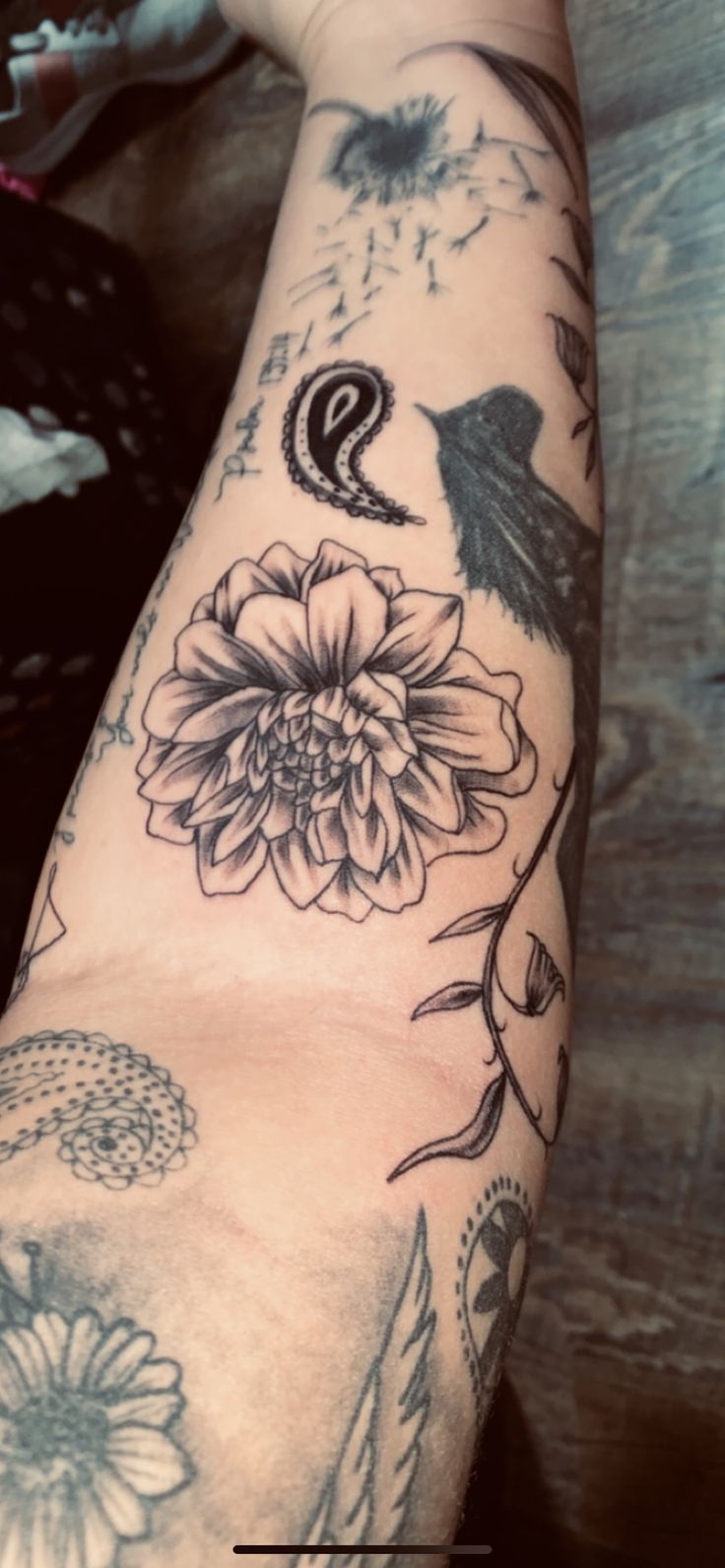 a person's arm with tattoos on it and a bird sitting on the flower