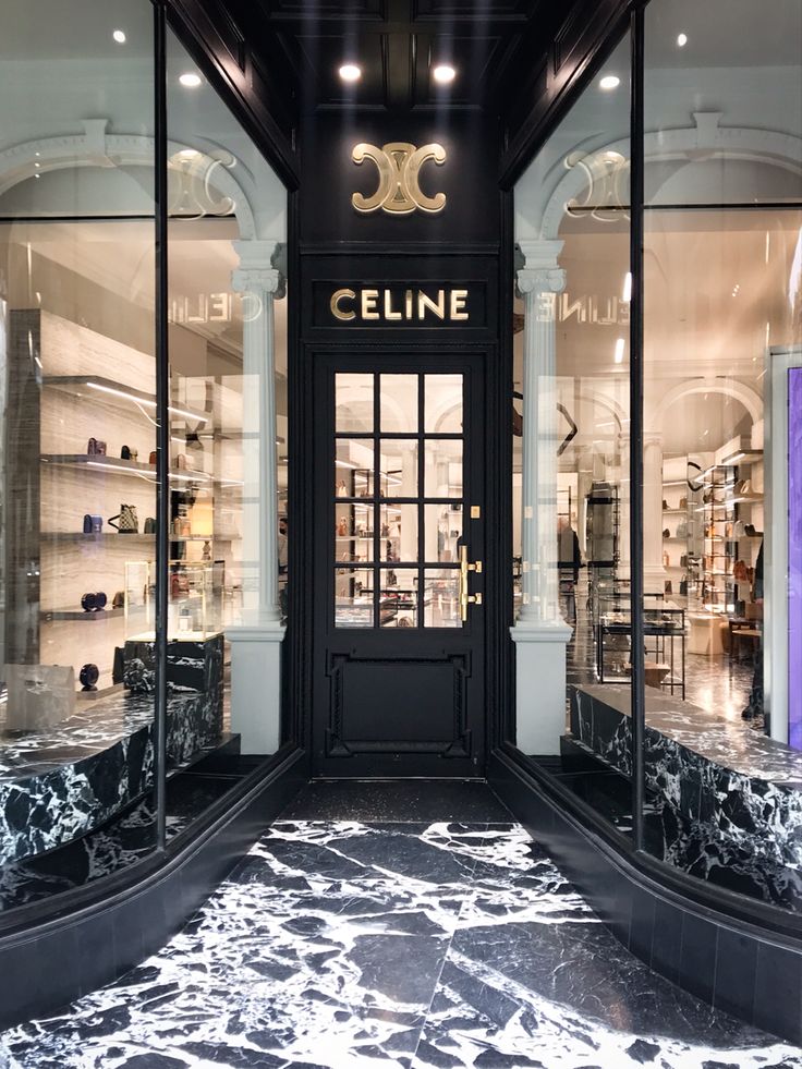 the entrance to a store with marble floors and black glass doors that read celine