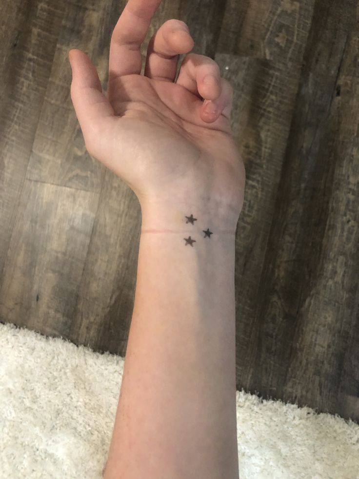 a woman's hand with a small star tattoo on it