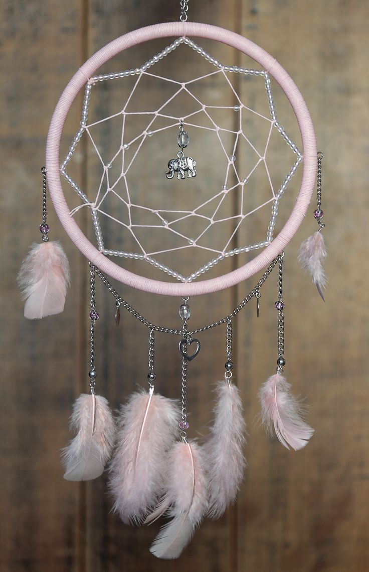 a pink dream catcher with feathers hanging from it