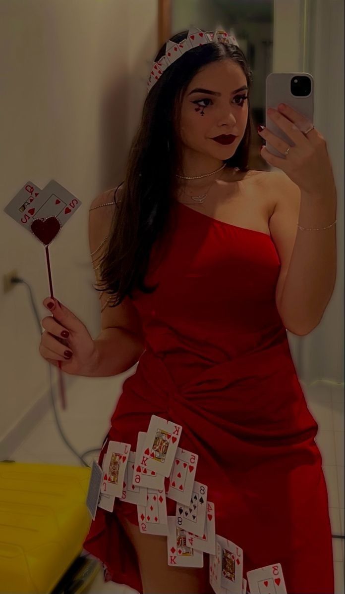 a woman in a red dress taking a selfie with her cell phone and playing cards