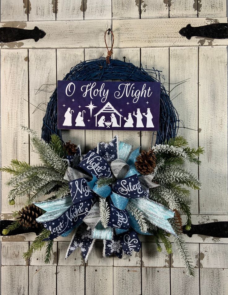 a christmas wreath hanging on the side of a wooden door with a nativity sign