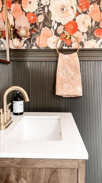 a bathroom sink sitting under a mirror next to a wooden cabinet with flowers on it