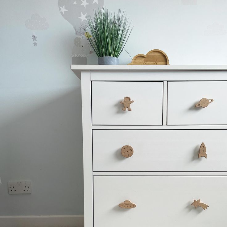 a white dresser with wooden birds on the handles and knobs in front of it