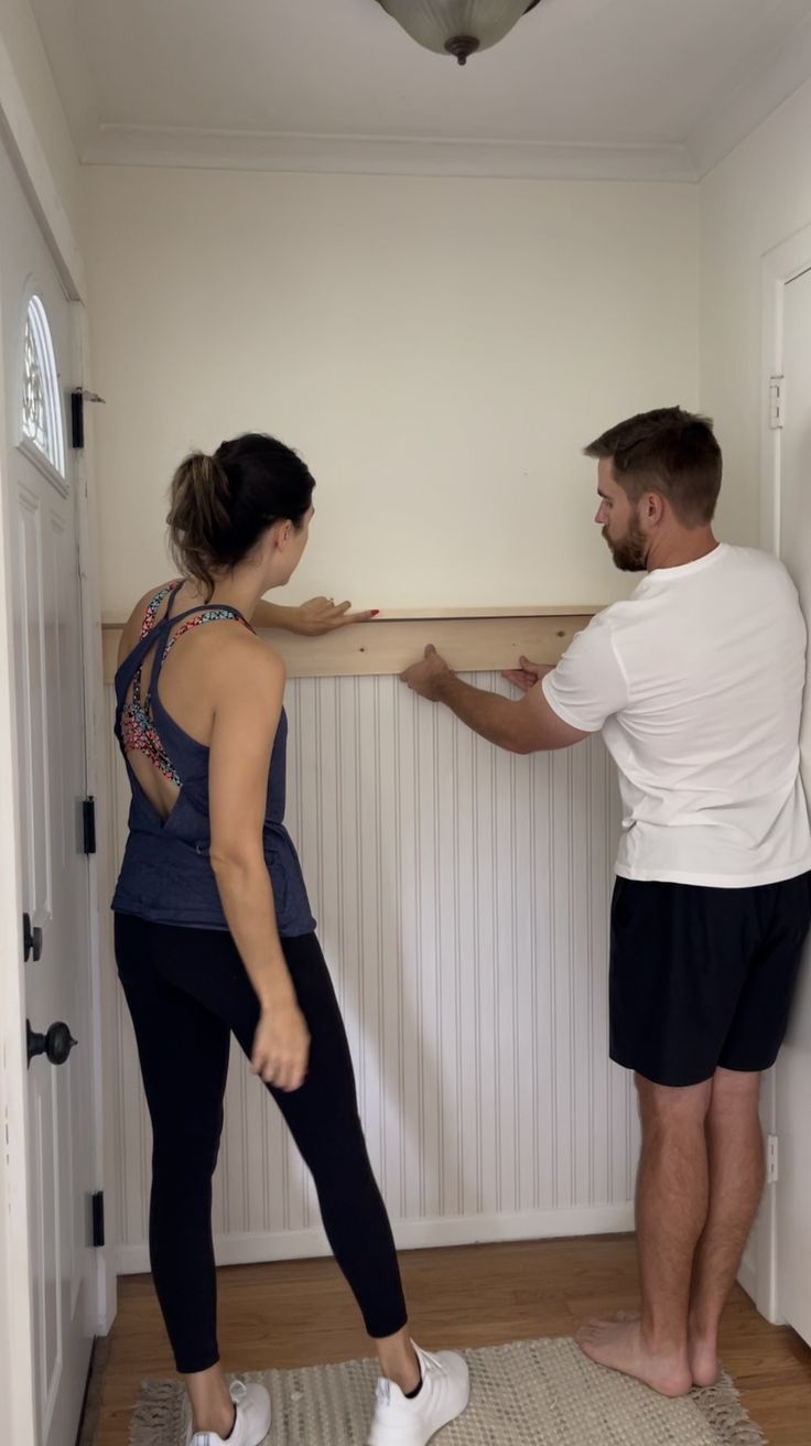 a man and woman standing next to each other in front of a wall mounted tv