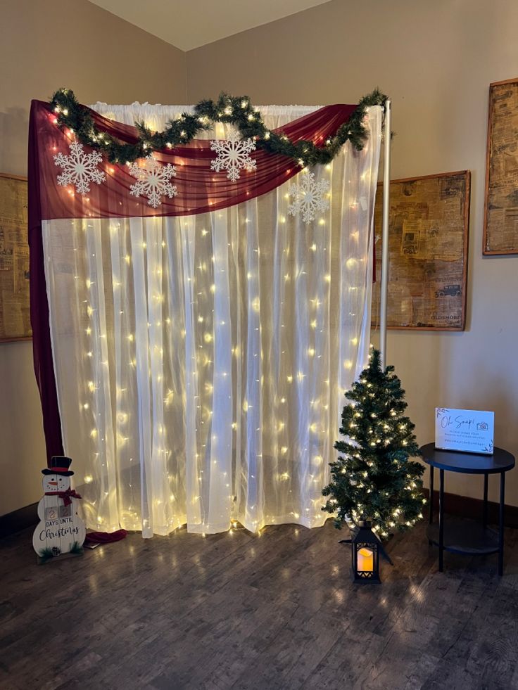 christmas decorations are displayed in front of a curtain with lights and snowflakes on it