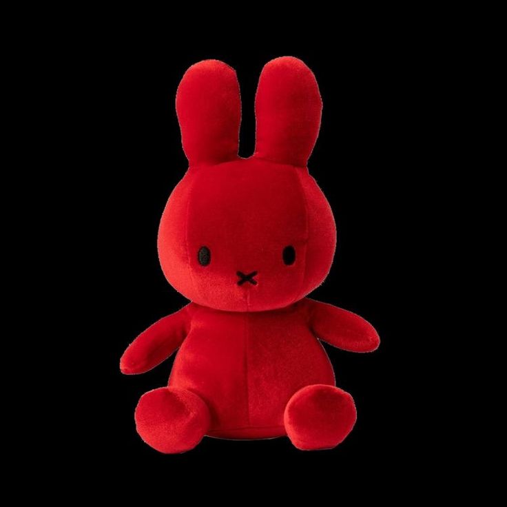 a red stuffed rabbit sitting in the dark