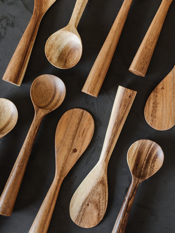 wooden spoons lined up next to each other on top of a black tablecloth