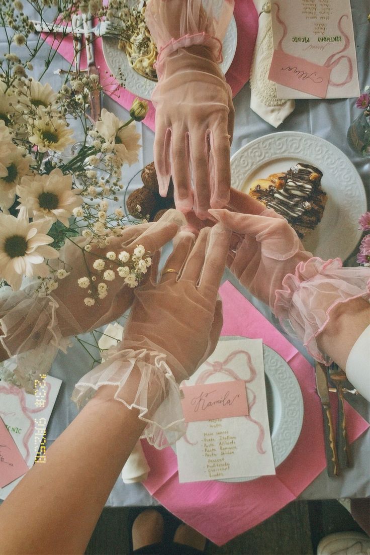 two hands reaching for each other at a table with flowers and napkins on it