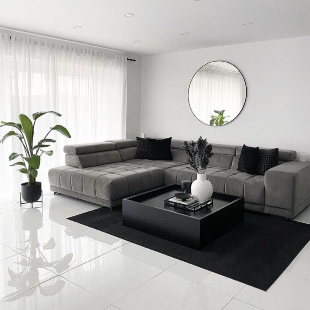 a living room filled with furniture and a large mirror on the wall above it's windows