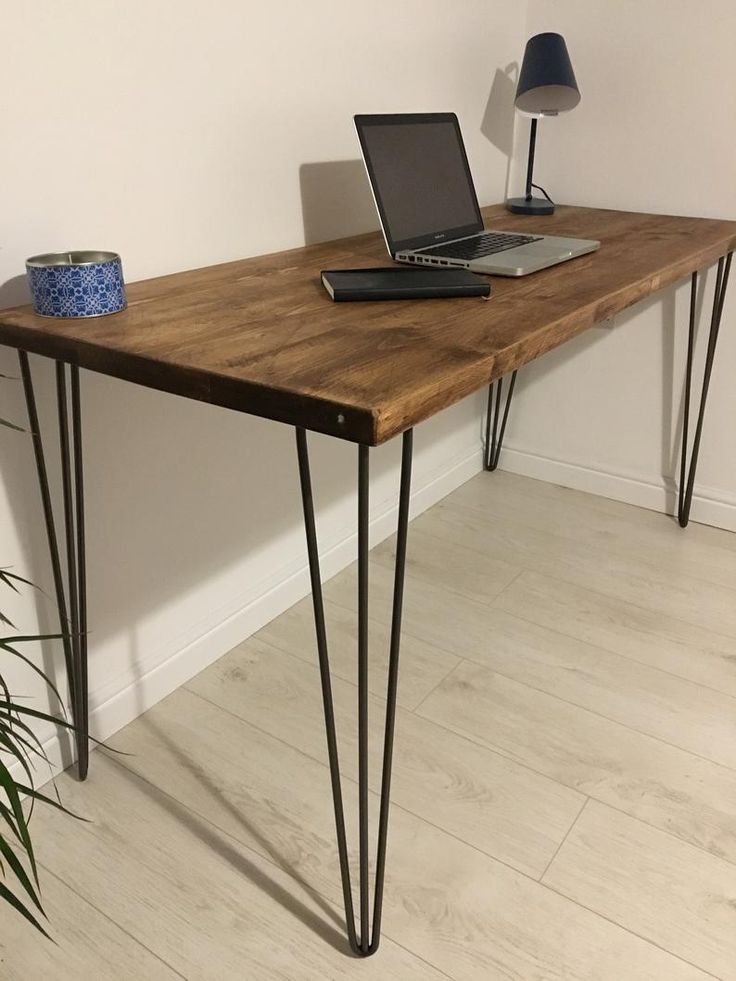 a laptop computer sitting on top of a wooden desk next to a plant and lamp