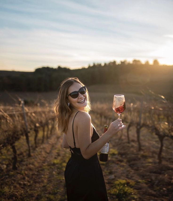 a woman wearing sunglasses holding a glass of wine