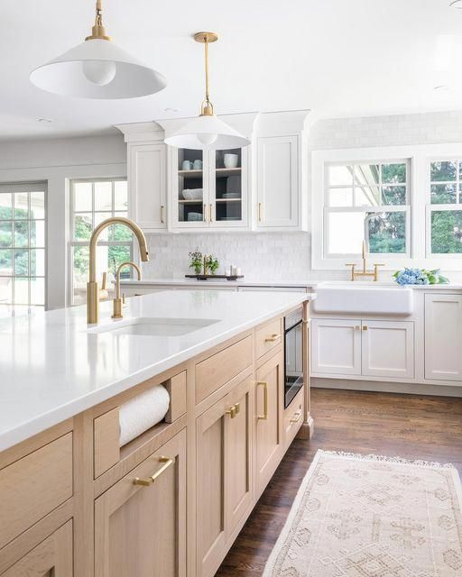 a large kitchen with white cabinets and gold hardware on the countertops, along with an area rug that matches the hardwood flooring