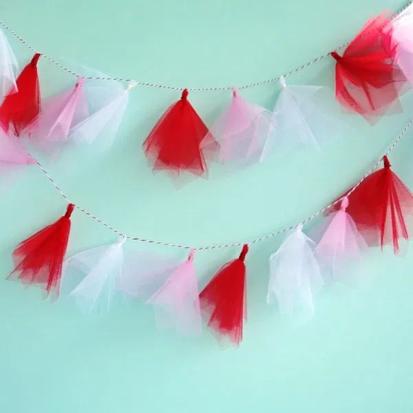 red and white tissue paper tassels hanging from a string on a green wall