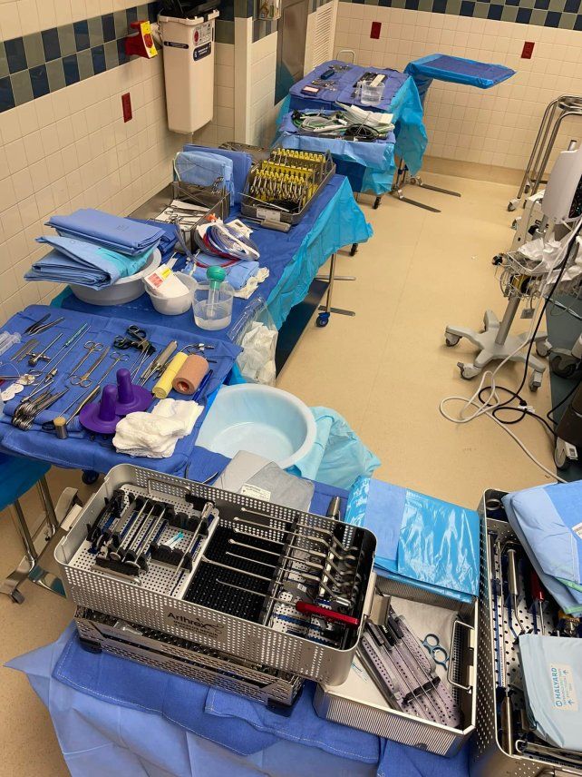 a room filled with lots of medical supplies and equipment on top of blue tables in front of white tiled walls