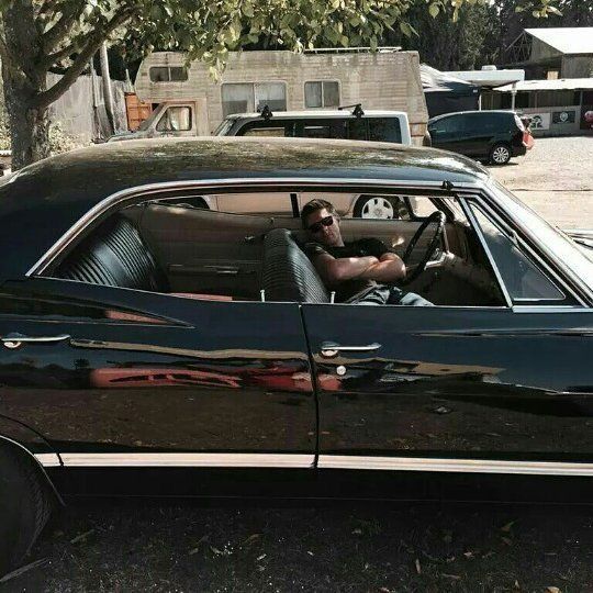 a man sitting in the driver's seat of a black car