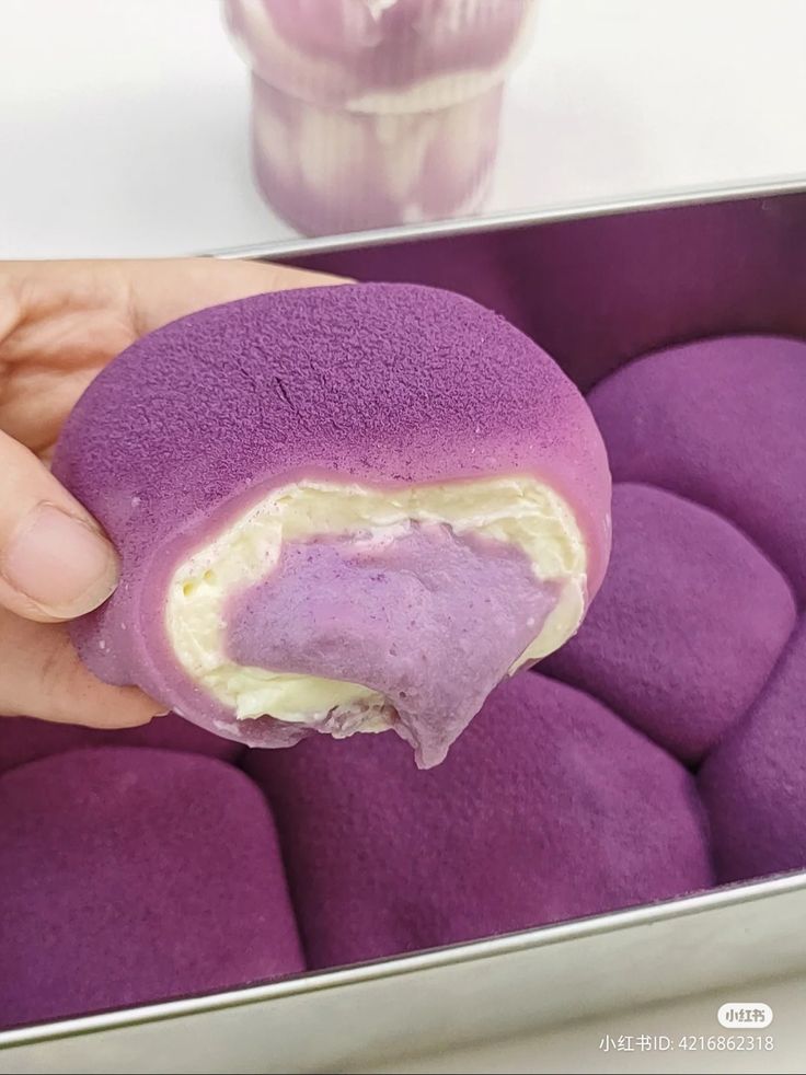 a person holding a purple doughnut in their hand