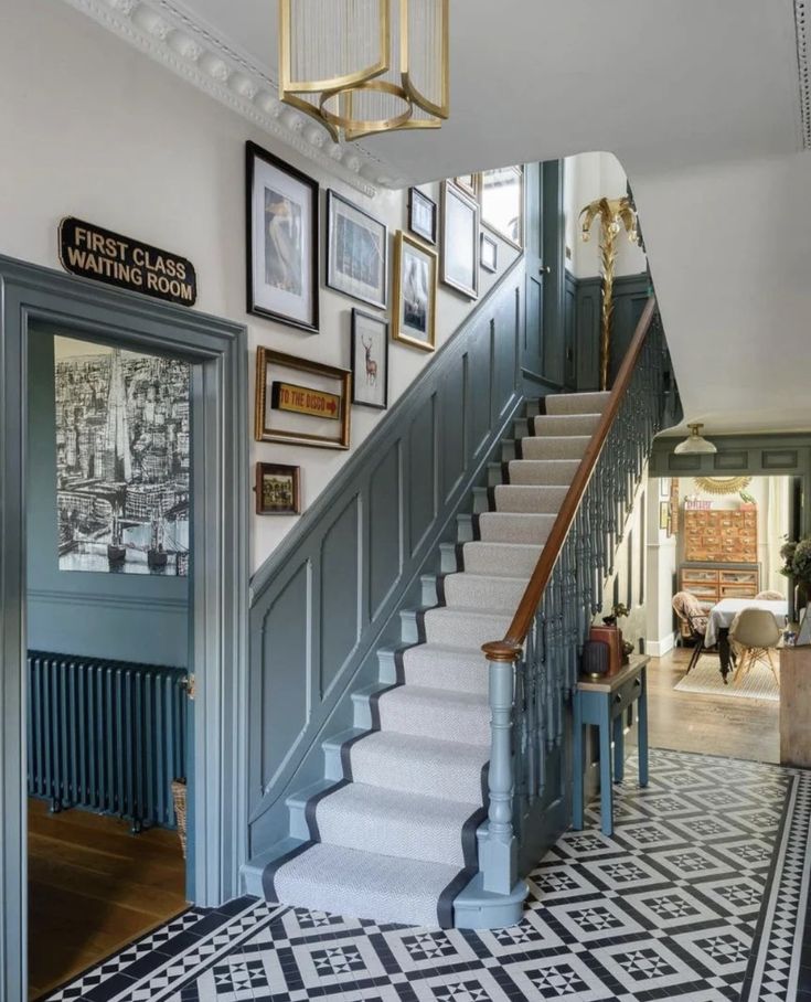 a staircase with pictures on the wall and framed photos on the wall above it, along with a black and white patterned rug