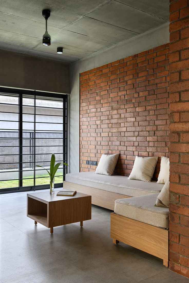 a living room with two couches and a coffee table in front of a brick wall