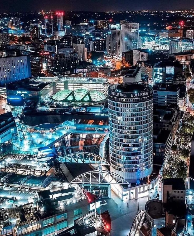 an aerial view of a city at night with lots of lights and buildings in the background