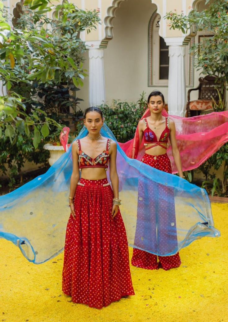 Bralette - handwoven silk, with hand embroidered florals in silk yarn with kashida and sozni, zardosi cutwork, sparkle and fun. Skirt - handwoven silk bandhini skirt with shells on the waistband. Dupatta - organza dupatta with beaten gold zardosi border and florals motifs in gold.. Red Art Silk Sets With Mirror Work, Bohemian Silk Set For Diwali, Red Silk Sharara With Mirror Work, Red Tissue Silk Sharara With Cutdana, Designer Red Tissue Silk Sharara, Bohemian Semi-stitched Silk Sharara, Semi-stitched Silk Bohemian Sharara, Bohemian Sharara With Dupatta For Reception, Transitional Red Organza Traditional Wear