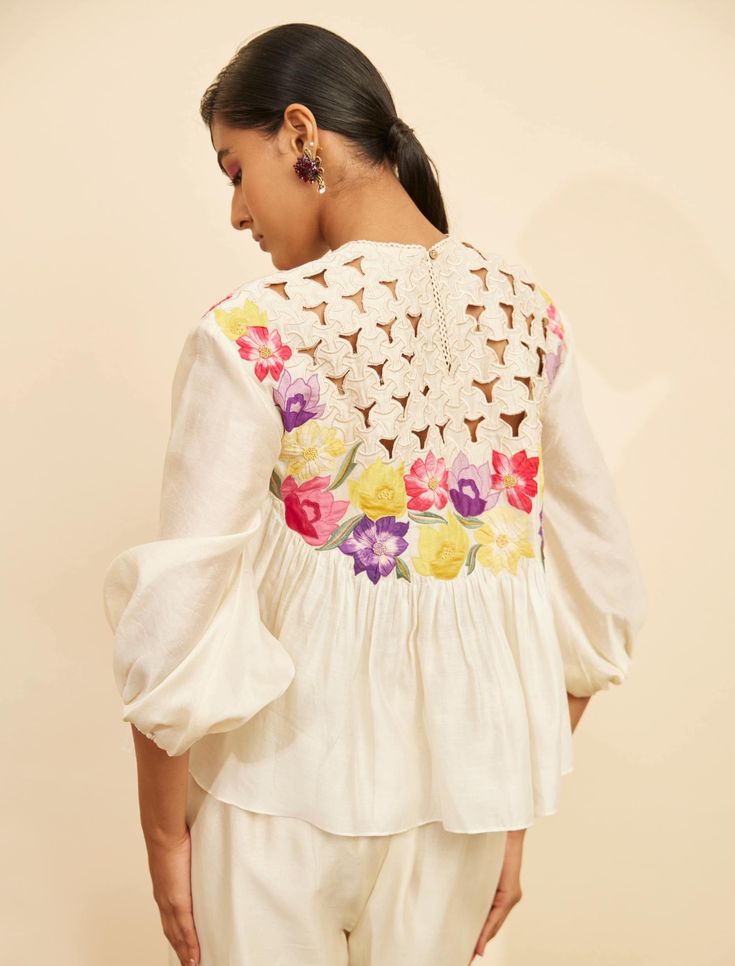 Editor's Note Featuring an ivory chanderi floral applique and cutwork top Note: Pant worn by model is for styling purposes and can be purchased separately. Color: Ivory Fabric: Chanderi Component: Top Occasion: Resort and daywear Care: Dry Clean Only About the Designer Chandrima celebrates diversity in cultures and craft forms creating ready-to-wear women wear for the urban woman of today. The brand embodies the idea of Indian handloom and craft merged with an international style. Label Chandrim White Long Sleeve Tops With Cutwork Hem, White Cutwork Hem Blouse For Summer, White Blouse With Cutwork Hem For Spring, White Cutwork Hem Summer Blouse, White Summer Blouse With Cutwork Hem, White Feminine Top With Cutwork Hem, Summer Cutwork Cotton Blouse, Summer Cotton Blouse With Cutwork, Summer Cotton Cutwork Blouse