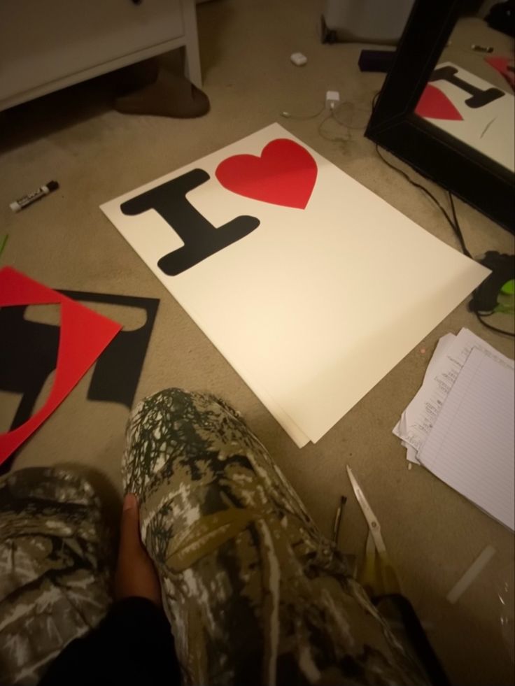 someone is sitting on the floor next to some cut out paper with i love letters