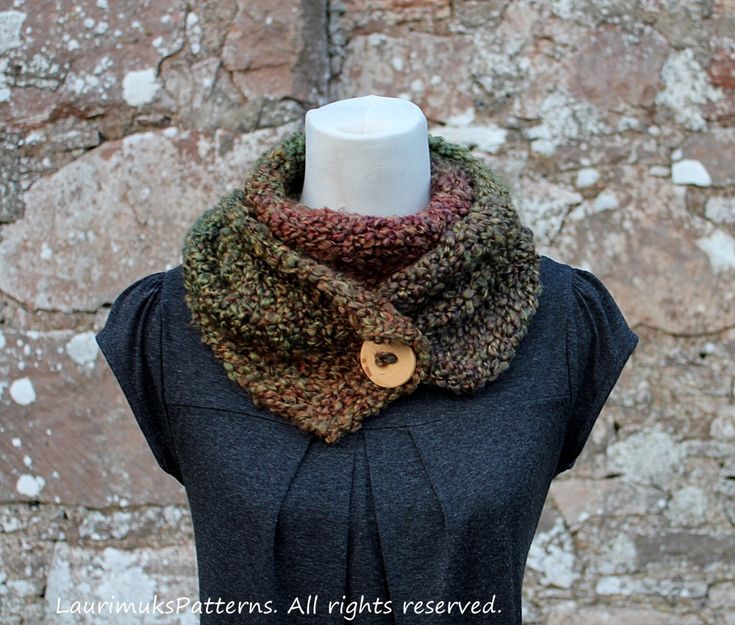 a knitted cowl with a wooden button sits on top of a mannequin