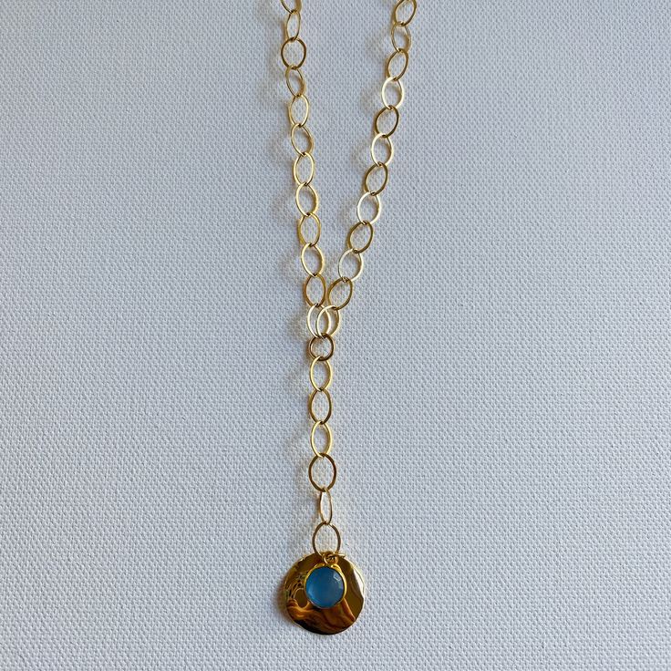 A blue sodalite gem is layered over a gold pendant and dangles from 2 inch lariat gold filled chain. The necklaces measures 18 inches and has a 3 inch lariat. Blue Jewelry With Detachable Pendant, Blue Jewelry With Detachable Round Pendant, Blue Long Necklace With Adjustable Chain, Bohemian Blue 14k Gold-filled Jewelry, Blue Bohemian 14k Gold Filled Jewelry, Bohemian Blue 14k Gold Filled Jewelry, Blue Necklace With Detachable Round Pendant, Blue Jewelry With Natural Stones For Layering, Blue Natural Stones Jewelry For Layering