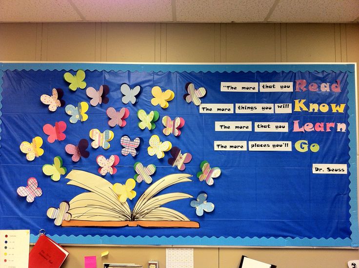 a bulletin board with butterflies on it and an open book in front of the wall