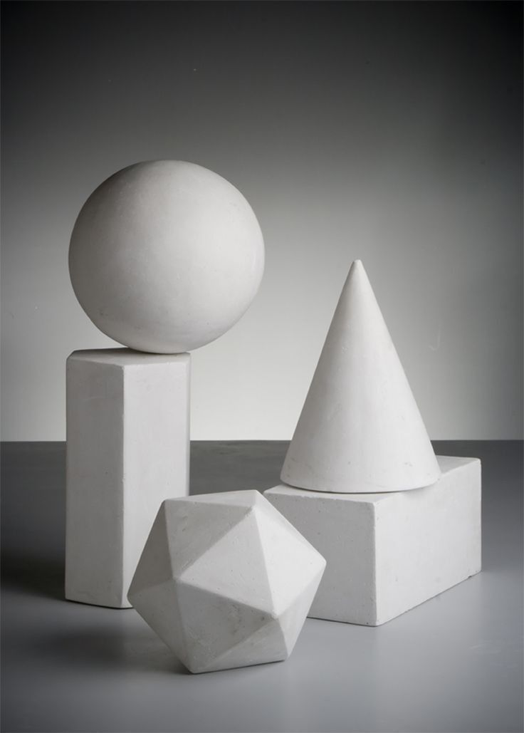 three white sculptures sitting next to each other on top of a table with a ball in the middle