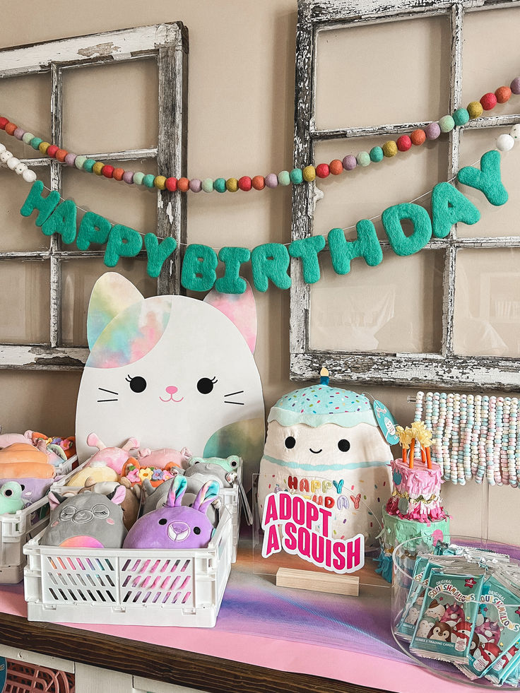 a table topped with lots of stuffed animals and toys next to a happy birthday sign