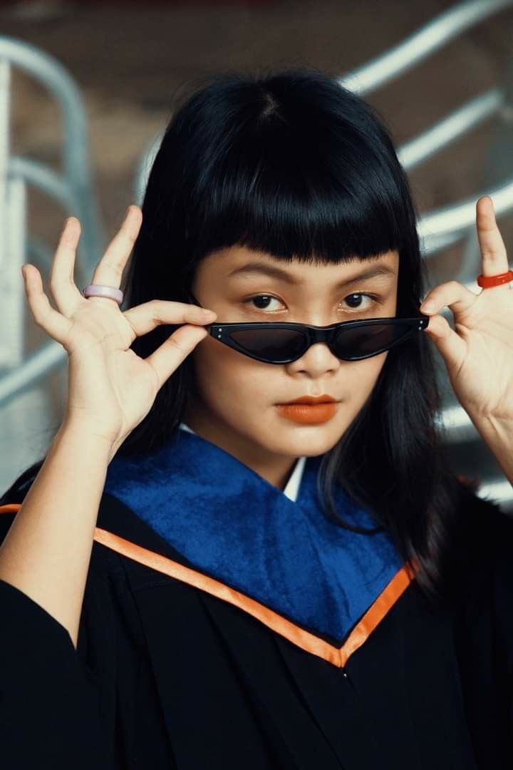 a woman wearing sunglasses and holding her hands up to the side with one eye open