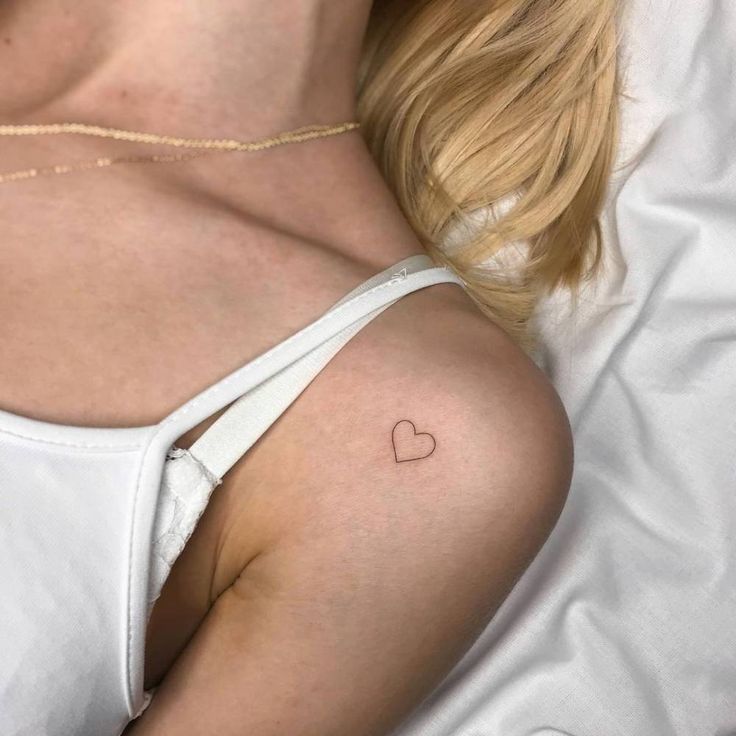 a woman with a small heart tattoo on her shoulder