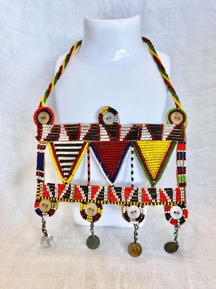 Please Read Full Description This vintage beaded Maasai necklace is a vibrant and authentic piece of hand crafted art from East Africa.  The Maasai artisans use a traditional technique with colorful glass beads intricately woven into beautiful patterns that reflect the rich cultural heritage of the Maasai people.  The necklace features eye-catching yellow, black, red and white beads sewn on a sturdy rigid base to keep the beads in place.  It is an elegant, statement-making piece of art.  To wear, the necklace slips over the head and hangs beautifully across the chest.  This necklace is in excellent condition.  All of the beads are intact. Measurements: Body of the necklace is 5 1/2" x 5 1/2".  The beaded string that slips around the neck is 21". FREE DOMESTIC SHIPPING   My vintage finds ar Handmade Necklaces For Traditional Ceremonies, Traditional Adjustable Necklace With Colorful Beads, Traditional Adjustable Necklaces With Colorful Beads, Traditional Handmade Beaded Necklaces For Ceremonies, Handmade Bohemian Necklaces For Traditional Ceremonies, Bohemian Handmade Beaded Necklaces For Traditional Ceremonies, Beaded Necklaces For Traditional Ceremonies And Festivals, Multicolor Beaded Necklaces For Traditional Ceremonies, Traditional Necklaces With Colorful Beads And Adjustable Fit