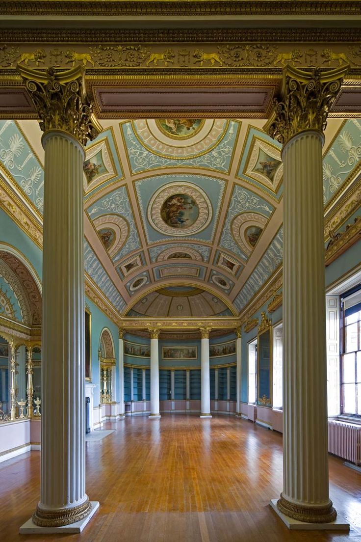 an empty room with columns and paintings on the walls, painted in blue and gold