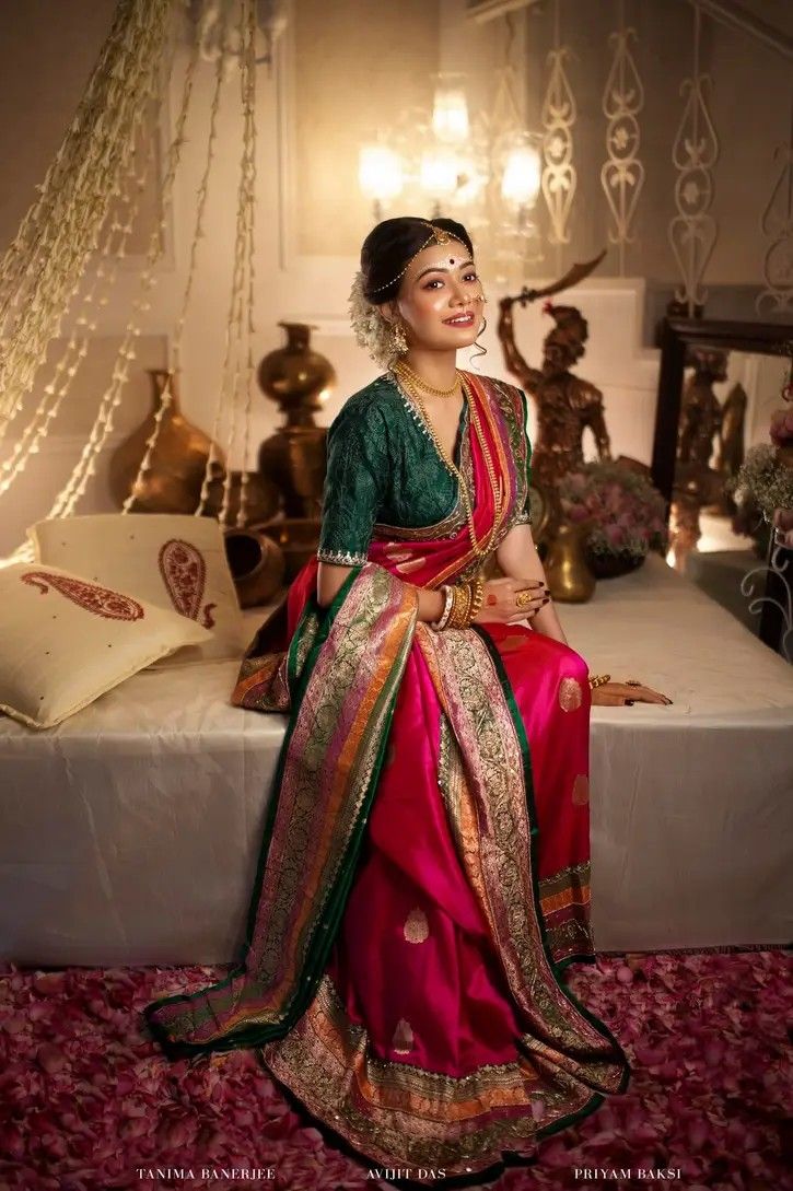 a woman sitting on top of a bed wearing a red and green sari dress