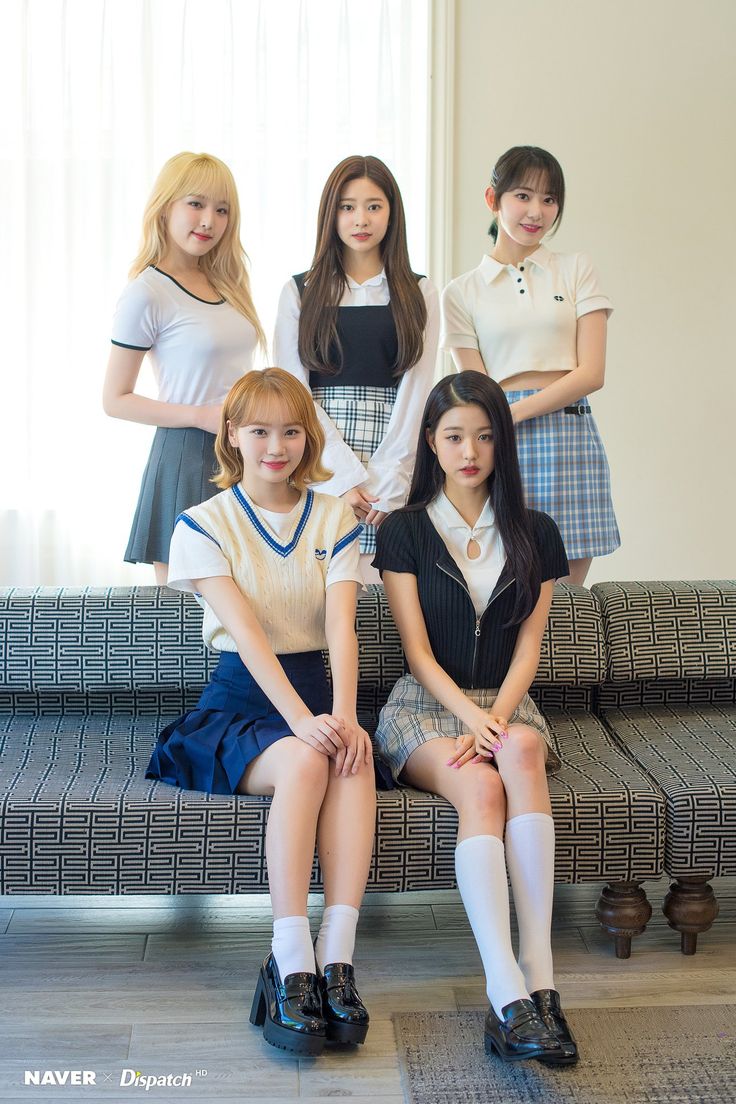 the girls are posing on the couch in front of the window, all wearing school uniforms