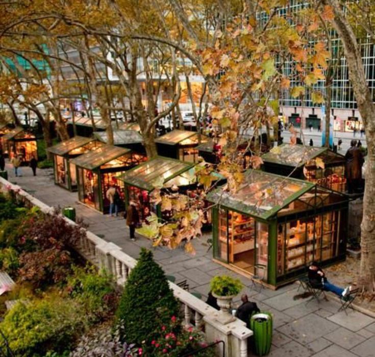 an aerial view of people walking around in the city with trees and buildings behind them