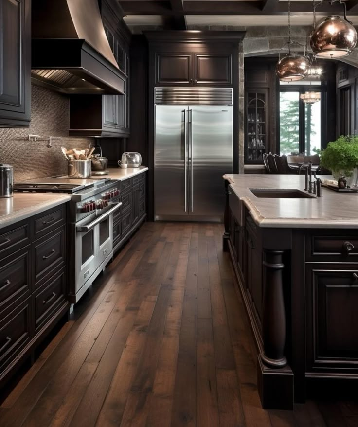 a large kitchen with wooden floors and black cabinets, stainless steel appliances and an island