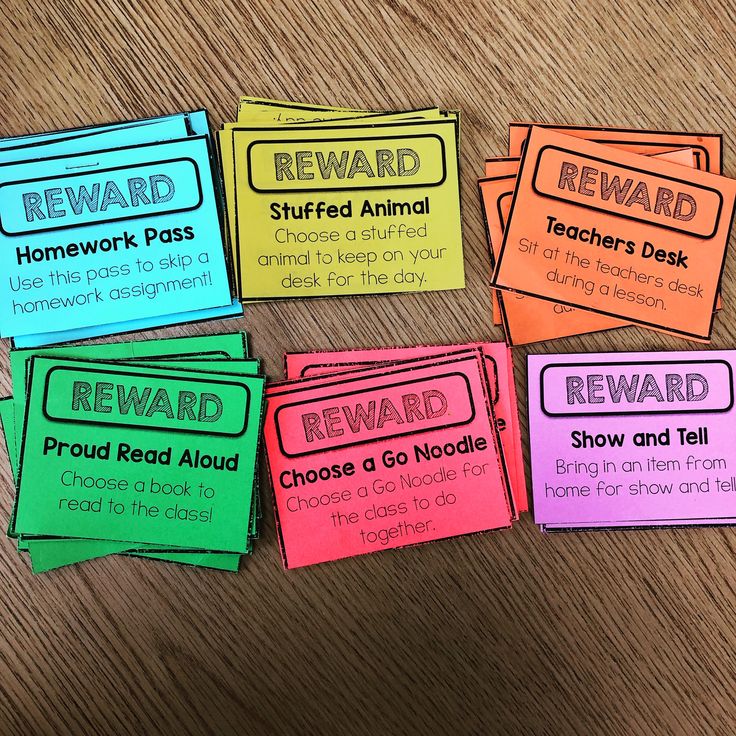 four reward cards on a wooden table with the words reward written in different colors and sizes